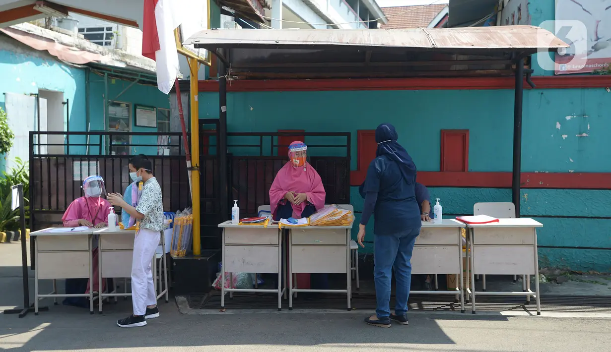 Guru SDIT Ibnu Sina memberikan tugas sekolah secara drive-thru kepada wali murid di Jakarta, Rabu (26/8/2020). Selama pembelajaran jarak jauh, siswa diwajibkan mengambil dan mengembalikan tugas di sekolah. (merdeka.com/Imam Buhori)