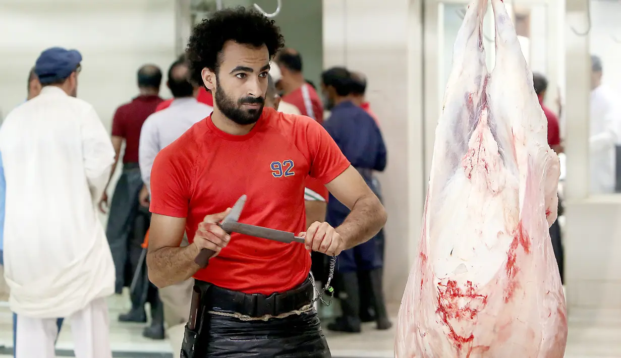 Mohammad Ibraheem, seorang tukang daging Mesir yang mirip dengan pemain Liverpool Mohamed Salah mengasah pisau saat bekerja di sebuah rumah jagal hewan di hari ketiga Idul Adha di Kota Kuwait (13/8/2019). (AFP Photo/Yasser Al-Zayyat)
