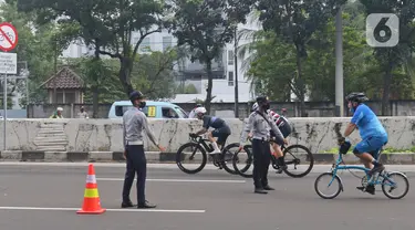 Petugas mengarahakan pesepeda non road bike saat memasuki JLNT Kampung Melayu-Tanah Abang, Jakarta, Minggu (30/5/2021). Dinas Perhubungan DKI Jakarta melakukan uji coba lintasan road bike JLNT Kampung Melayu-Tanah Abang tahap kedua pada pukul 05.00-08.00 WIB. (Liputan6.com/Herman Zakharia)