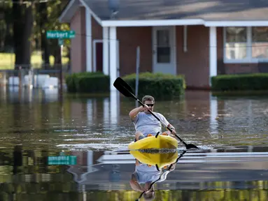 Parker Uzzell mendayung kano untuk aktivitas di tengah banjir yang melanda wilayah Lumberton di Carolina Utara, Amerika Serikat, 12 Oktober 2016. Banjir akibat badai Matthew tersebut merendam kota berpenduduk 21.000 orang itu. (REUTERS/Randall Hill)