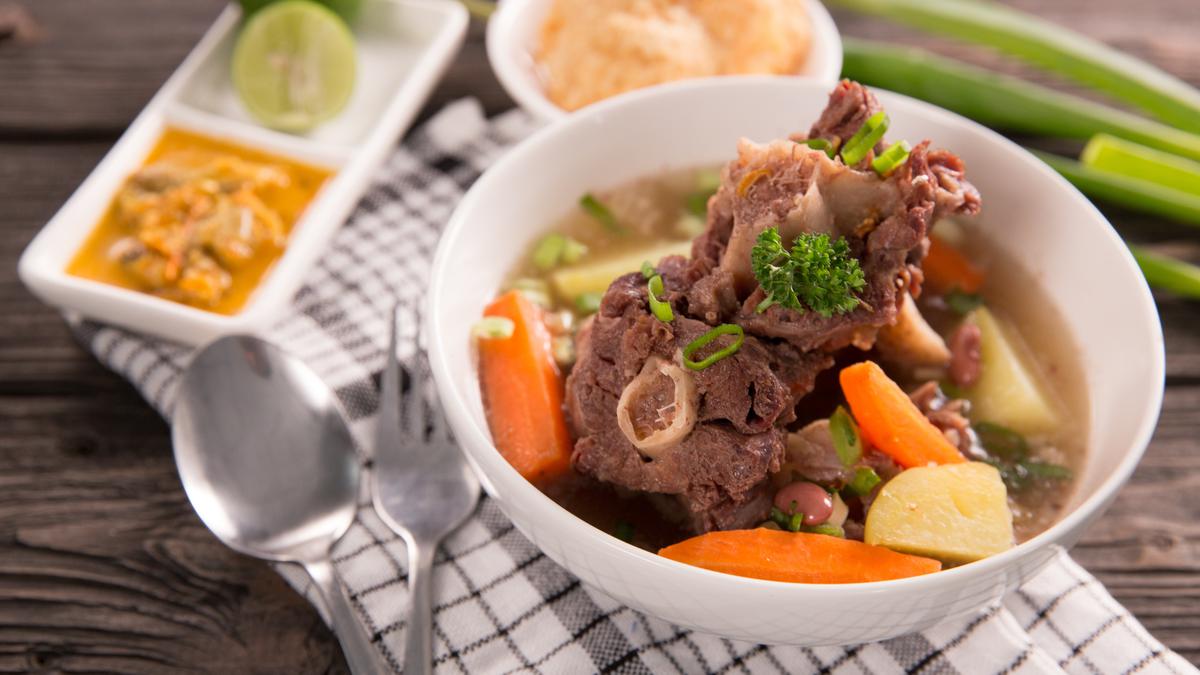 Semangkuk sop buntut sapi dengan kuah bening yang gurih, dilengkapi potongan daging empuk, wortel, dan kentang, siap disajikan hangat