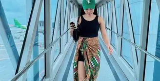 Siapa bilang kain batik tak bisa digunakan secara kasual? Lihat airport look ala Yura Yunita di sini. Ia mengenakan tank top hitam, dipasangkannya dengan kain batik bernuansa hijau yang senada dengan topi yang dikenakannya. Foto: Instagram.
