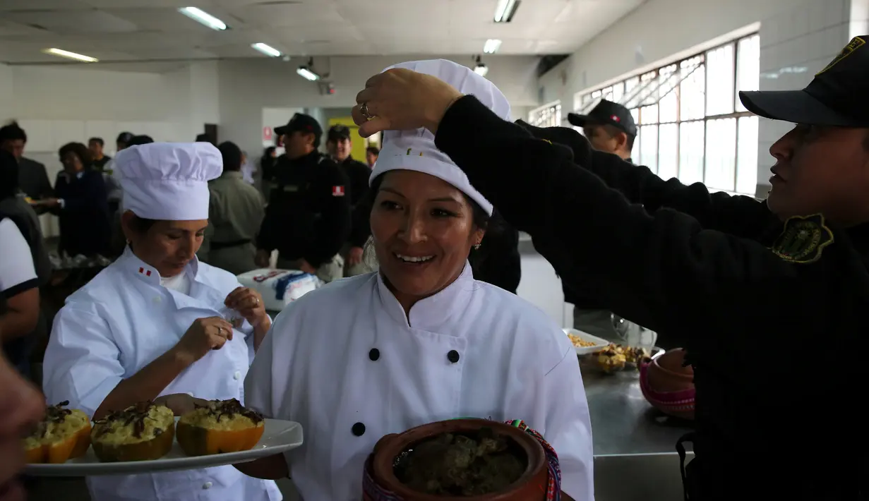Petugas merapikan topi narapidana sebelum menyajikan masakannya dalam kompetisi kuliner 'INPE Mistura 2016' di penjara perempuan Chorrillos di Lima, Rabu (7/9). Sejumlah penjaga penjara memperhatikan dan mengawasi secara seksama. (REUTERS/Mariana Bazo)