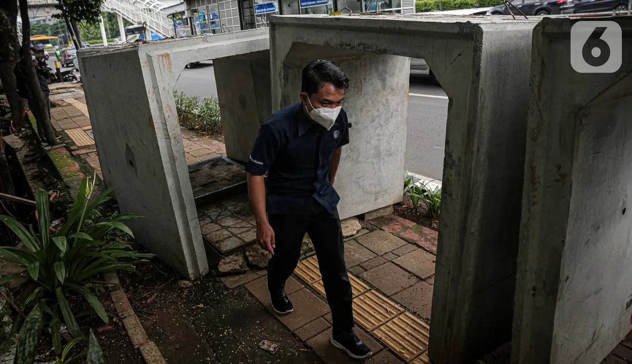 Pejalan kaki melintas di samping beton saluaran air yang berada di jalur pedestrian kawasan Gatot Subroto, Jakarta, Selasa (21/12/2021). Selain mengganggu kenyamanan, keberadaan beton saluran air tersebut juga dapat membahayakan pejalan kaki yang melintas. (Liputan6.com/Faizal Fanani)