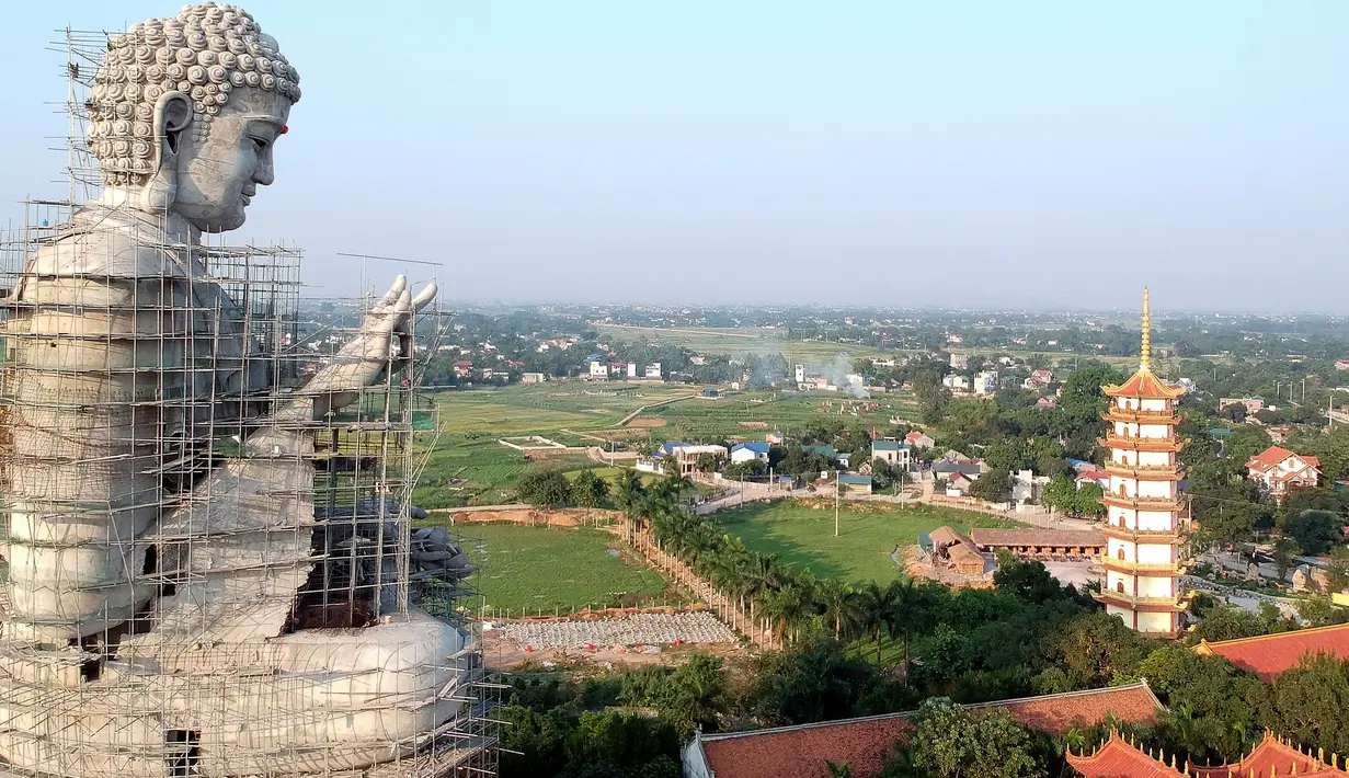 Foto udara pada 18 Mei 2019 memperlihatkan patung Buddha raksasa yang sedang dibangun di pagoda Khai Nguyen di distrik Son Tay, pinggiran Hanoi. Pengerjaan patung Buddha setinggi 72 meter ini dimulai pada 2015 dan diperkirakan selesai dalam lima tahun mendatang. (Photo by Manan VATSYAYANA/AFP)