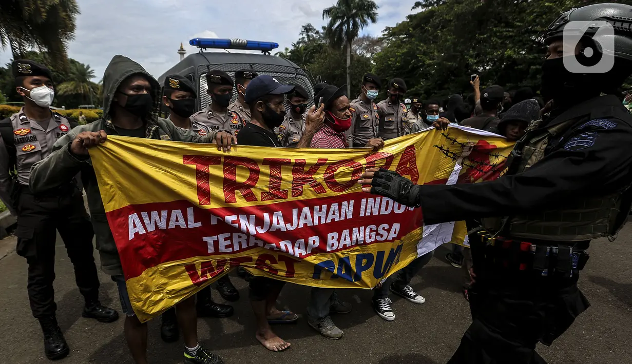 Polisi menjaga masyarakat Papua yang memperingati Operasi Trikora 19 Desember 1961 di Patung Kuda, Jakarta, Sabtu (19/12/2020). Massa juga menuntut penghentian rasisme dan politik rasial. (Liputan6.com/Johan Tallo)