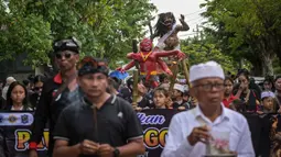 Acara ini berlangsung meriah melibatkan arak-arakan patung raksasa sebagai simbol pembersihan unsur negatif, serta menampilkan perpaduan budaya Bali dan ikon khas Surabaya. Tampak dalam foto, seorang penganut Hindu membawa Ogoh-ogoh, patung yang melambangkan roh jahat, selama pawai menjelang Nyepi di Surabaya pada Rabu 18 Maret 2026. (JUNI KRISWANTO/AFP)