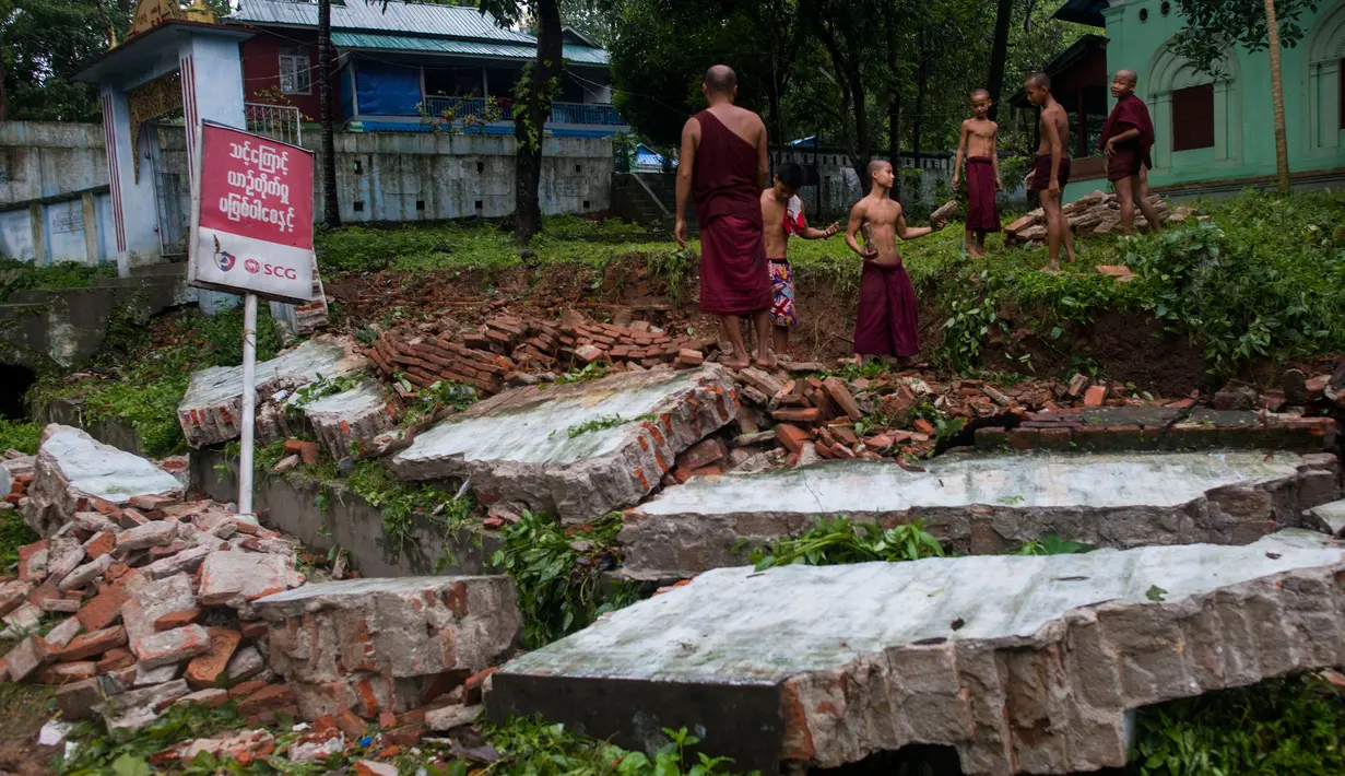 Sejumlah Biksu Buddha membersihkan puing-puing akibat tanah longsor yang merusak pagodha di puncak bukit Kyeik Than Lan Myanmar (18/6). Banjir di Myanmar Selatan juga merendam ratusan rumah. (AFP PHOTO / Ye Aung Thu)