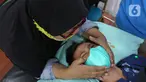 Seorang ibu berusaha menenangkan anaknya saat disunat di Puskesmas Kecamatan Cilandak, Jakarta, Kamis (2/12/2021). Sebanyak 50 anak mengikuti kegiatan sunat massal secara gratis dalam rangka Hari Kesehatan Nasional ke-57 mulai Selasa (30/11) hingga Juma (3/12). (Liputan6.com/Herman Zakharia)