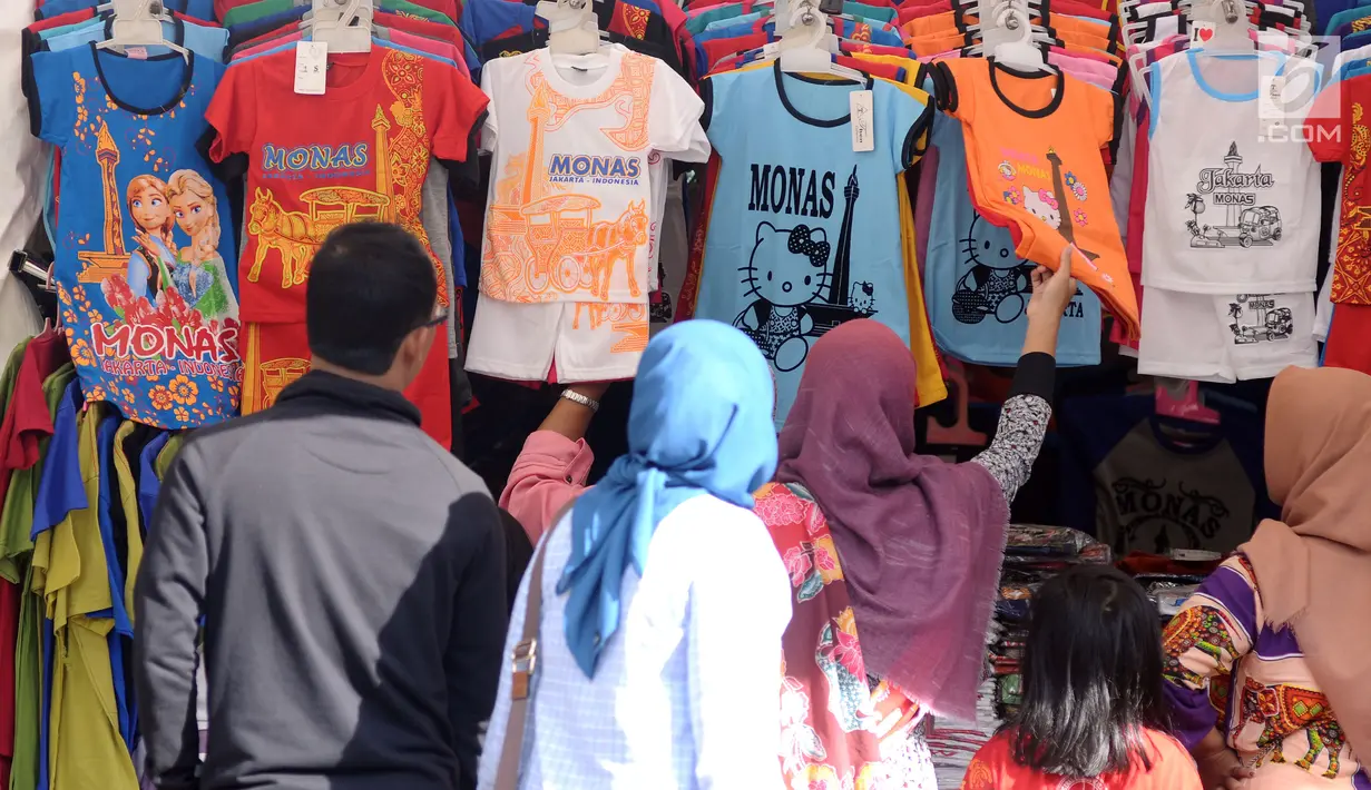 Pengunjung memilih kaus cenderamata di kawasan Monumen Nasional, Jakarta, Senin (25/12). Libur perayaan Natal dimanfaatkan warga untuk berwisata di kawasan Monumen Nasional. (Liputan6.com/Helmi Fithriansyah)