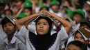 Para pelajar muda meletakkan buku di kepala mereka saat berkumpul di pusat evakuasi yang telah ditentukan di luar gedung sekolah selama latihan gempa bumi di salah satu sekolah dasar di Manila, Filipina pada 11 September 2025. (Ted ALJIBE/AFP)