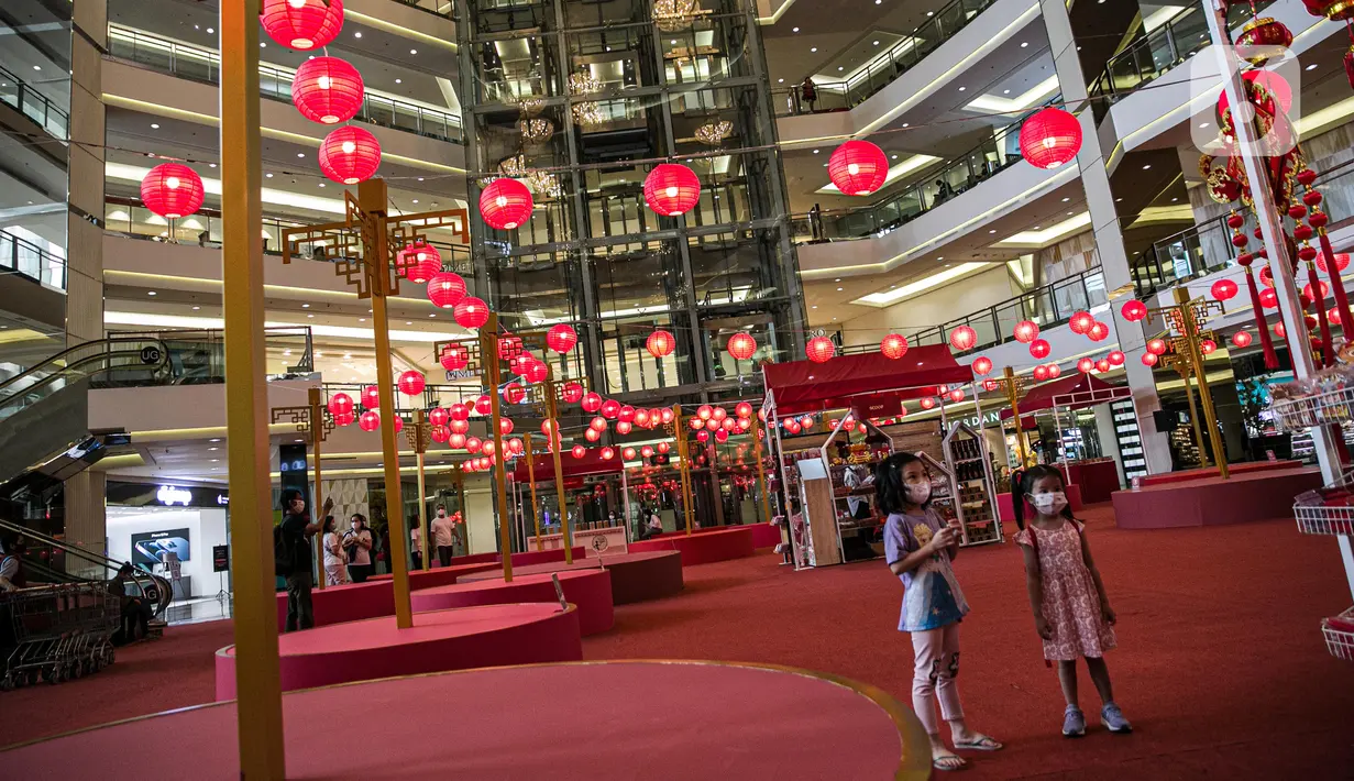 Anak-anak mengamati berbagai hiasan berwarna merah hingga lampion yang menghiasi Mall Taman Anggrek, Jakarta, Kamis (28/1/2021). Hiasan tersebut dalam rangka memeriahkan perayaan Tahun Baru Imlek 2572 atau Tahun Kerbau Logam. (Liputan6.com/Faizal Fanani)