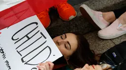 Anna Hurley (15) bersama dengan pengunjuk rasa lainnya berbaring di jalan depan Gedung Putih, Washington, Senin (19/2). Aksi mereka merupakan simbol dari para korban tewas penembakan sekolah di Florida pekan lalu. (AP Photo/Evan Vucci)