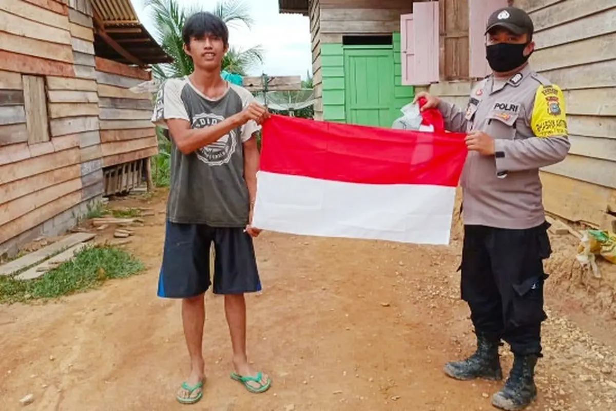 Suku Talang Mamak menerima bendera merah putih yang diberikan personel Polres Indragiri Hulu.