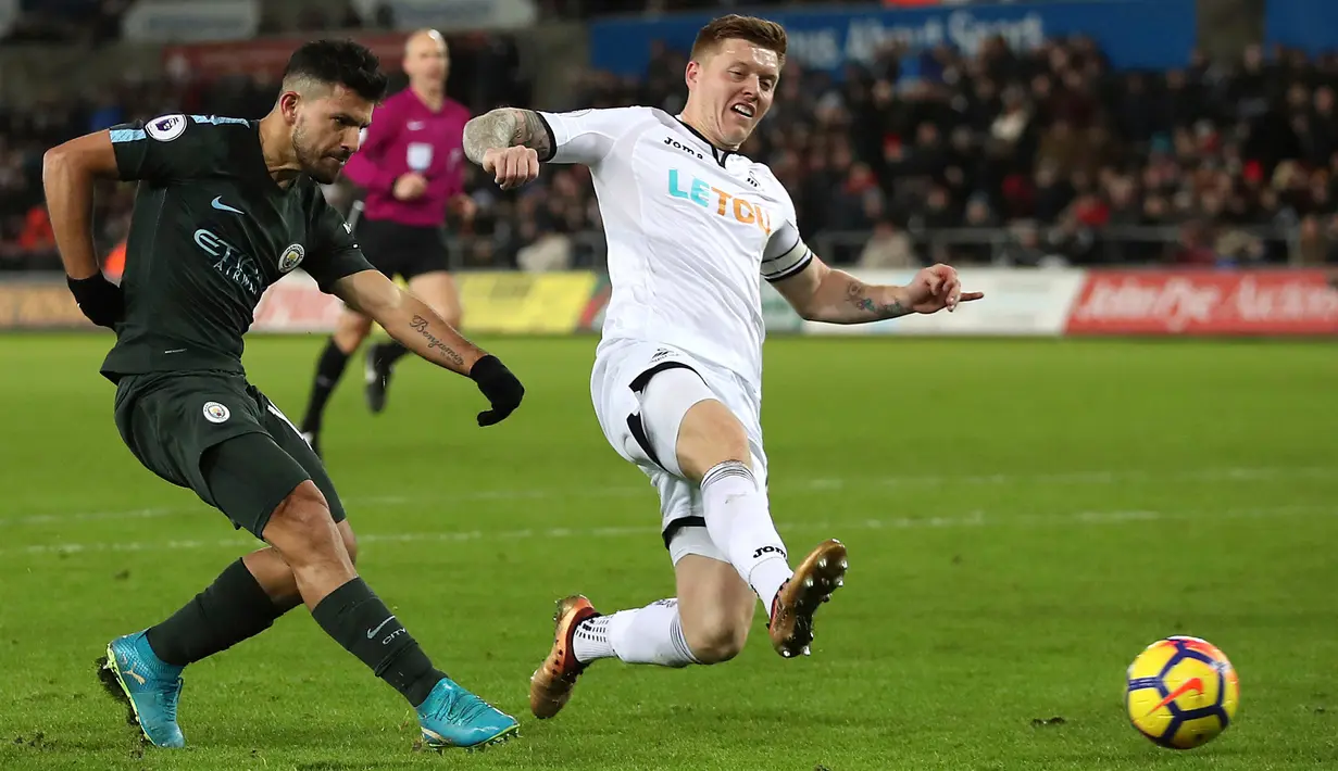 Pemain Manchester City, Sergio Aguero melakukan tendangan ke gawang Swansea City pada lanjutan Premier League, di Liberty Stadium, Rabu (13/12). Man City mencatatkan rekor 15 kemenangan berturut-turut usai menang dengan skor 4-0. (Nick Potts/PA via AP)