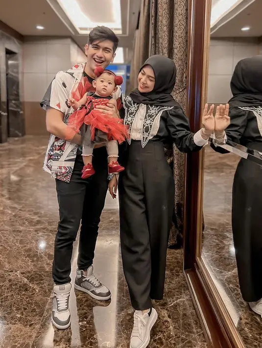 Ria Ricis tampil serba hitam dari kerudung hingga celananya. Sedangak si kecil tampil dengan dress merah tutu. (@riaricis1795)