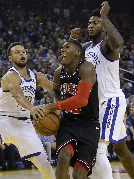 Pemain Chicago Bulls, Kris Dunn (tengah) berusaha melewati adangan pemain Golden State Warriors pada laga NBA basketball game di Oracle Arena, Oakland, (24/11/2017). Warriors menang 143-94. (AP/Jeff Chiu)