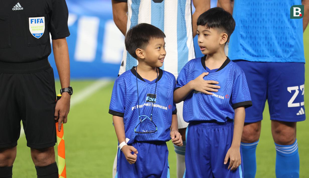 Cucu Presiden RI Joko Widodo, Jan Ethes (kanan) bercengkrama dengan rekannya saat menjadi player escort pemain Timnas Argentina pada laga FIFA Matchday melawan Timnas Indonesia di Stadion Utama Gelora Bung Karno (SUGBK), Senayan, Jakarta, Senin (19/06/2023). (Bola.com/Bagaskara Lazuardi)