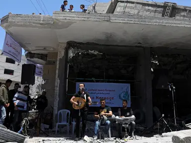 Seorang penyanyi Palestina tampil selama acara musik di puing-puing bangunan yang baru-baru ini hancur oleh serangan udara Israel di kota Gaza, Selasa (14/5/2019). Aksi tersebut untuk menyerukan pemboikotan terhadap Kontes Lagu Eurovision 2019 yang diselenggarakan di Israel. (REUTERS/Mohammed Salem)