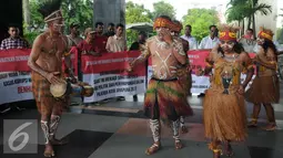 Sejumlah pemuda Papua mengenakan pakaian adat menari saat menggelar unjuk rasa di depan Gedung KPK, Jakarta, Senin (19/12). Mereka melakukan aksi teaterikal dan meminta KPK mengusut sejumlah kasus dugaan korupsi. (Liputan6.com/Helmi Affandi)