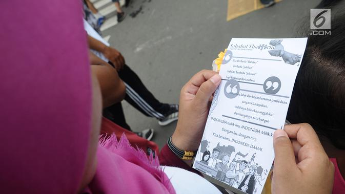 Warga membaca selebaran kertas di kawasan Thamrin, Jakarta, Minggu (13/1). Komunitas Sahabat Thamrin mengenang tragedi 3 tahun bom Thamrin dengan tema 'Menerima Perbedaan untuk Merayakan Kebersamaan dan Perdamaian'. (Liputan6.com/Herman Zakharia)