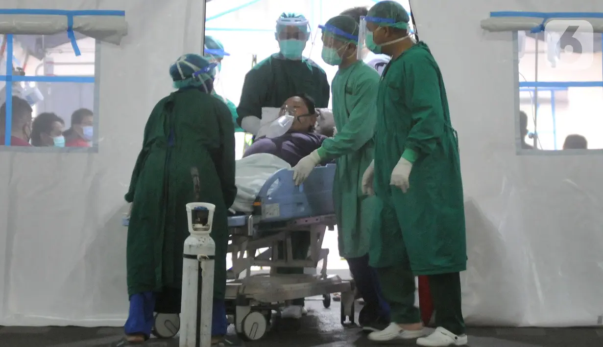 Petugas medis mendorong pasien yang terpasang alat oksigen di atas tempat tidur di RSUD Cengkareng, Jakarta, Kamis (24/6/2021). Lonjakan kasus virus corona mengakibatkan ruang IGD penuh, pihak rumah sakit lantas mendirikan tenda darurat untuk merawat pasien covid-19. (merdeka.com/Arie Basuki)
