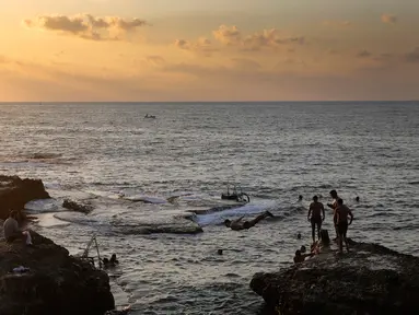 Sejumlah orang berenang di laut Mediterania dari Corniche, atau promenade tepi laut saat matahari terbenam selama hari terakhir musim panas, di Beirut, Lebanon (20/9). (AP Photo / Hussein Malla)