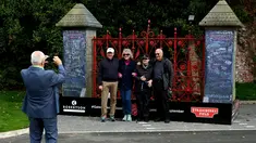 Pengunjung berpose di depan gerbang  Strawberry Fields yang baru dibuka untuk umum di Liverpool, Rabu (18/9/2019). Strawberry Field menjadi salah satu tempat ikonis ketika John Lennon menulis lagu The Beatles “Strawberry Fields Forever” dalam album Sgt.pepper Lonely Hearts Club Band (Paul ELLIS/AFP)