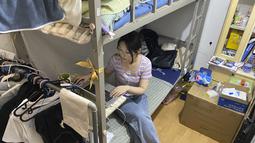 Lulusan perguruan tinggi baru-baru ini Liu Qian bekerja di komputer laptopnya di kamar yang dia sewa di sebuah apartemen di Beijing, Kamis, 7 Juli 2022.  Liu adalah salah satu dari 11 juta lulusan baru yang putus asa untuk bekerja di pasar kerja yang suram karena lockdown COVID memaksa pabrik, restoran, dan pengusaha lainnya untuk tutup. Para penyintas memotong pekerjaan dan upah. (AP Photo/Olivia Zhang)