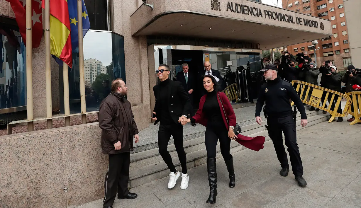 Pemain Juventus Cristiano Ronaldo menggandeng kekasihnya Georgina Rodriguez saat meninggalkan pengadilan di Kota Madrid, Spanyol, Selasa (22/1). Ronaldo melemparkan senyum kepada para jurnalis yang menantinya. (AP Photo/Manu Fernandez)