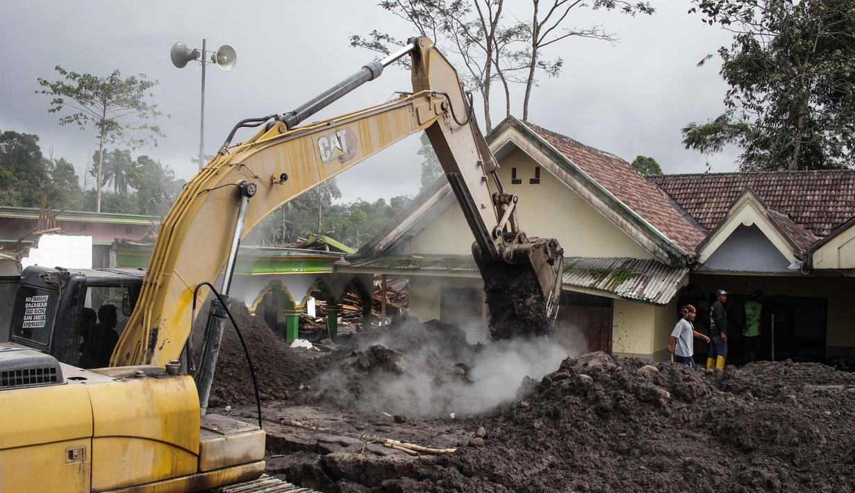 Ratusan warga terpaksa mengungsi dan tinggal di tempat penampungan sementara. Tampak dalam foto, alat berat membersihkan abu di depan sebuah rumah yang hancur akibat aliran piroklastik Gunung Semeru di Desa Supiturang, Lumajang, Jawa Timur, pada Jumat 21 November 2025. (Agus Harianto/AFP)