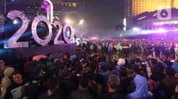 Warga berkerumun menikmati salah satu panggung hiburan di Bundaran Hotel Indonesia, Jakarta, Selasa (31/12/2019). Meski Jakarta diguyur hujan sejak Selasa (31/12) sore, warga tetap antusias melewati malam pergantian tahun 2019 menuju 2020 di kawasan Bundaran HI Jakarta. (Liputan6.com/Angga Yuniar)