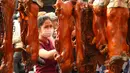 Seorang wanita melihat babi panggang di pasar di Phnom Penh, Kamboja (4/2). Menyambut Tahun Baru Imlek, warga Kamboja mempersiapkan daging babi panggang untuk sajian makan. (AFP Photo/Tang Chhin Sothy)