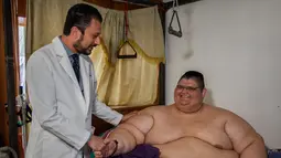 Juan Pedro Franco bersama dokter yang merawatnya selama ini di kediamannya di Guadalajara, Meksiko (28/3). Pria tergemuk di dunia ini berat badannya turun 170 kilogram setelah dirinya mengikuti diet selama 4 bulan. (AFP Photo / Hector Guerrero)