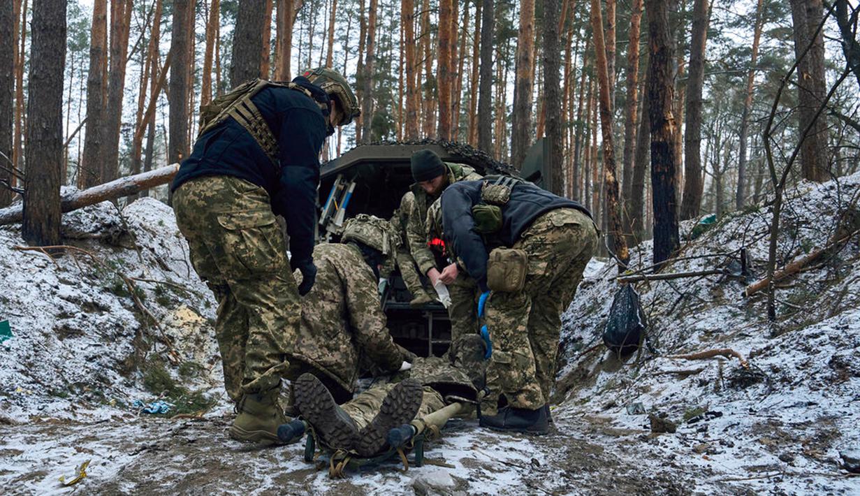 Petugas medis militer memberikan pertolongan pertama kepada seorang tentara yang terluka parah dekat Kremenna di wilayah Luhansk, Ukraina, 16 Januari 2023. Hingga saat ini pejabat Ukraina menolak untuk mengonfirmasi jumlah korban dalam perangnya dengan Rusia, setelah ketua Komisi Uni Eropa pada akhir November 2022 lalu memperkirakan bahwa "lebih dari 20.000 warga sipil dan 100.000 tentara Ukraina telah tewas di Ukraina hingga saat ini." (AP Photo/LIBKOS)
