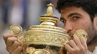 Selebrasi petenis Spanyol, Carlos Alcaraz dengan mencium trofi juara setelah memastikan kemenagan atas petenis Serbia, Novak Djokovic pada laga final tunggal putra turnamen tenis Grand Slam Wimbledon 2023 di All England Lawn and Tennis Club, London, Minggu (16/7/2023) malam WIB. Carlos Alcaraz menang 3-2 (1-6, 7-6 (6), 6-1, 3-6 dan 6-4). (AP Photo/Kirsty Wigglesworth)