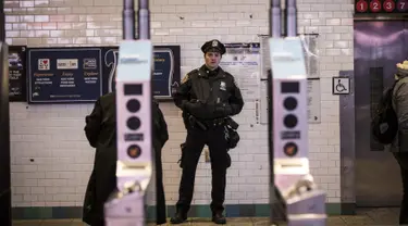 Petugas kepolisian New York berjaga di pintu masuk stasiun kereta bawah tanah Times Square saat jam sibuk malam di New York City, Senin (11/12). Sebelumnya ledakan bom terjadi di terminal bawah tanah kawasan Manhattan. (Drew Angerer/Getty Images/AFP)