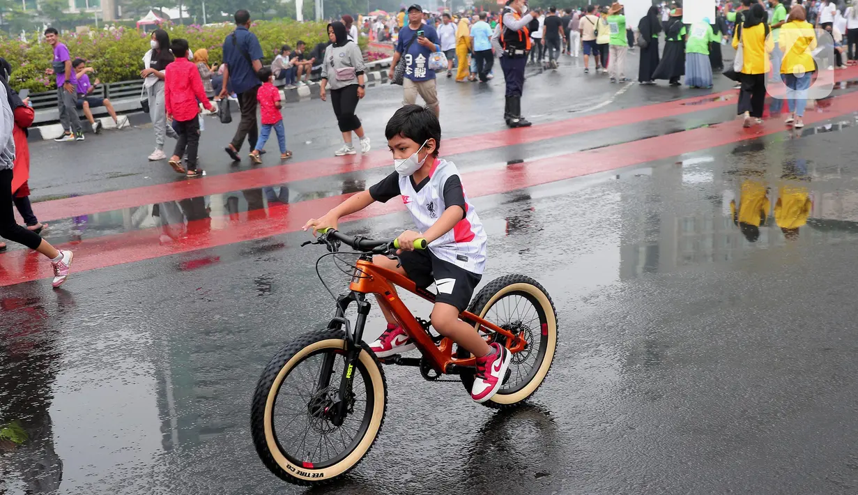 Seorang anak mengendarai sepeda saat CFD di kawasan Bundaran HI, Jakarta, Minggu (3/7/2022). Meski sempat diguyur hujan tidak menyurutkan  masyarak untuk berolahraga di akhir pekan. (Liputan6.com/Angga Yuniar)