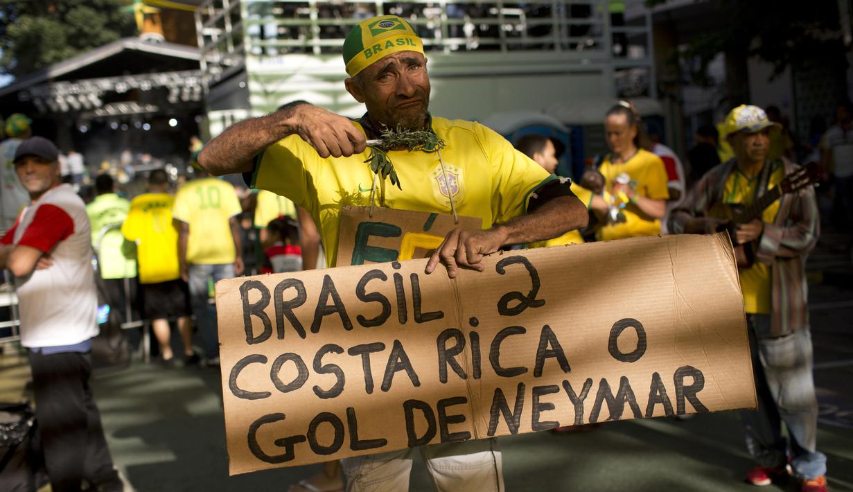 Seorang suporter menunjukan hasil akhir Brasil melawan Kosta Rika pada laga grup E Piala Dunia 2018 di Rio de Janeiro, Brasil, (22/6/2018). Brasil menang 2-0. (AP/Silvia Izquierdo)