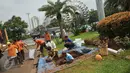 Pekerja mengangkut tanah saat pembuatan sumur resapan di Monas, Jakarta, Jumat (22/7). Pembuatan puluhan sumur resapan itu guna mengantisipasi genangan air hujan dan menyimpan air di Kawasan Monas dan depan Istana Merdeka. (Liputan6.com/Gempur M Surya)