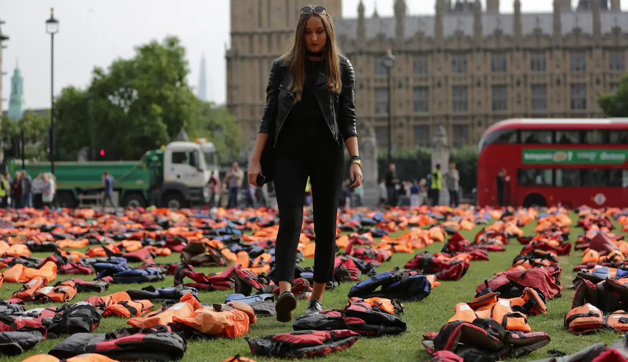 Seorang wanita berdiri di antara ribuan jaket pelampung para pengungsi, yang dipajang di dekat Gedung Parlemen London, Inggris, Senin (19/9). Aksi ini untuk memfokuskan KTT PBB tentang Mengatasi Gerakan Besar Pengungsi dan Migran. (Daniel Leal-Olivas/AFP)