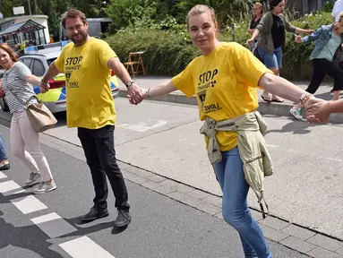Demonstran membentuk rantai manusia untuk menuntut penutupan reaktor nuklir Belgia yang sudah menua di Aachen, Jerman barat, 25 Juni 2017. Aksi rantai manusia ini melintasi wilayah tiga negara, Jerman, Belgia dan Belanda. (Henning Kaiser / dpa / AFP)