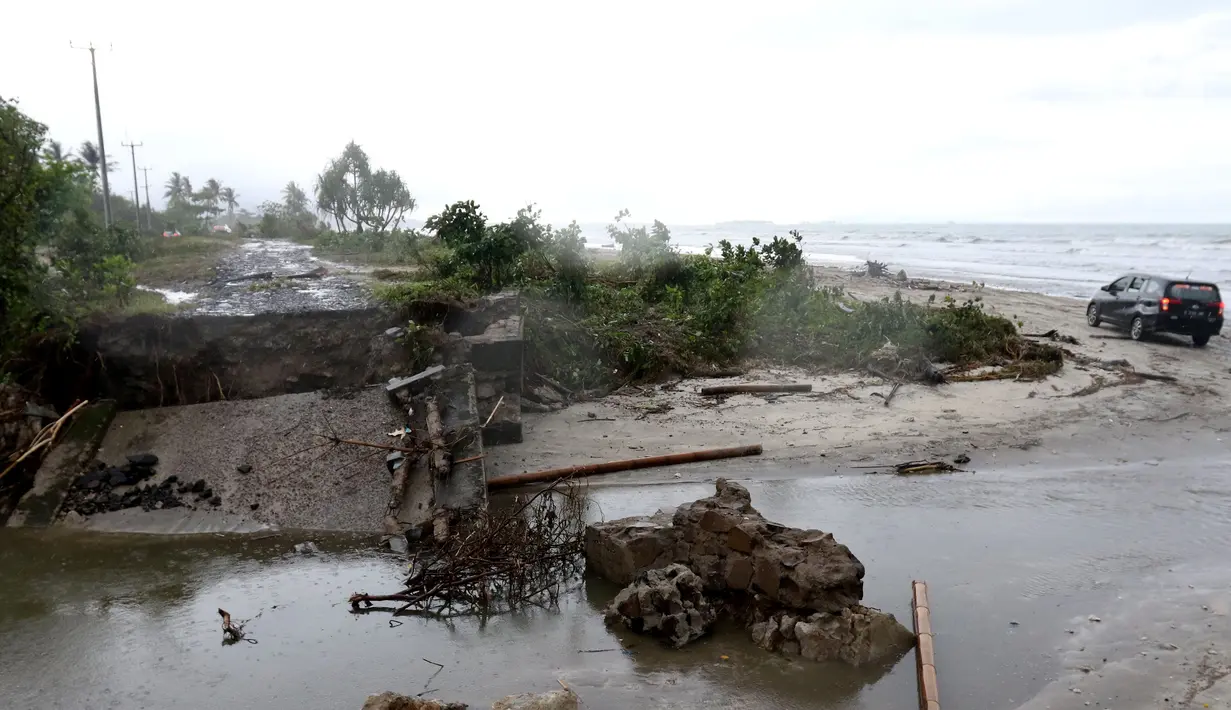 Sebuah mobil melintasi pantai karena jembatan di jalur alternatif Sumur, Banten, ambruk, Senin (24/12). Jembatan penghubung ambruk diterjang gelombang Tsunami Selat Sunda. (Liputan6.com/Angga Yuniar)