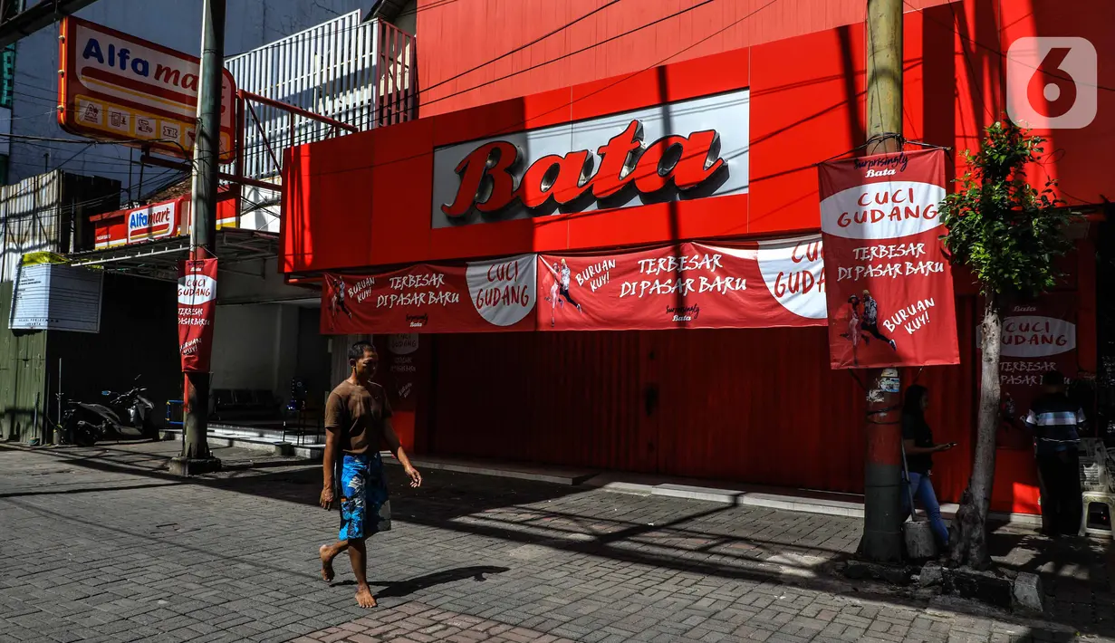 Warga berjalan Suasana di depan pertokoan kawasan perdagangan Pasar Baru yang tutup, Jakarta, Jumat (3/4/2020). Sebagian pemilik toko di Pasar Baru memilih menutup usahanya sementara waktu untuk mengantisipasi meluasnya penyebaran virus corona COVID-19. (Liputan6.com/Faizal Fanani)