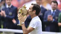 Roger Federer mencium trofi Wimbledon setelah mengalahkan Marin Cilic 6-3, 6-1, 6-4 di final, Minggu (16/7/2017). Ini adalah gelar kedelapan Federer di ajang tersebut. (AFP/Glyn Kirk)
