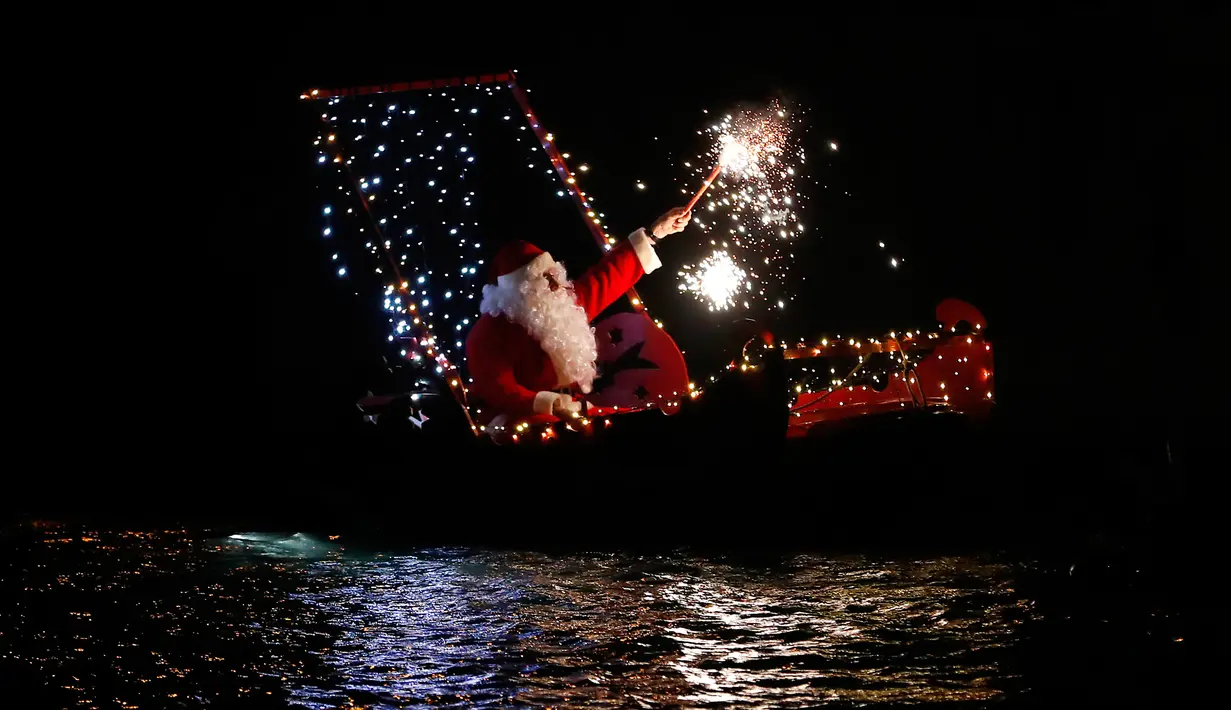 Seorang pria mengenakan kostum Santa Claus bermain kembang api di atas kapal selama perayaan malam Natal di Imperia, Italia (24/12). (AP Photo/Antonio Calanni)