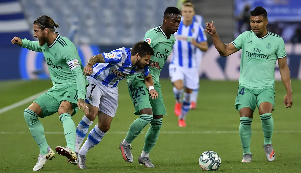 Pemain Real Sociedad, Portu, berusaha melewati pemain Real Madrid pada laga La Liga di Reale Seguros Stadium, Minggu (21/6/2020). Real Madrid menang 2-1 atas Real Sociedad. (AP Photo/Alvaro Barrientos)