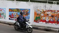 Pengendara motor melintasi mural bertema Pemilu 2019 di kawasan Dukuh Atas, Jakarta, Senin (1/4). Mural-mural tersebut dibuat dalam rangka menyukseskan Pemilu yang akan berlangsung pada 17 April 2019 mendatang. (Liputan6.com/Immanuel Antonius)