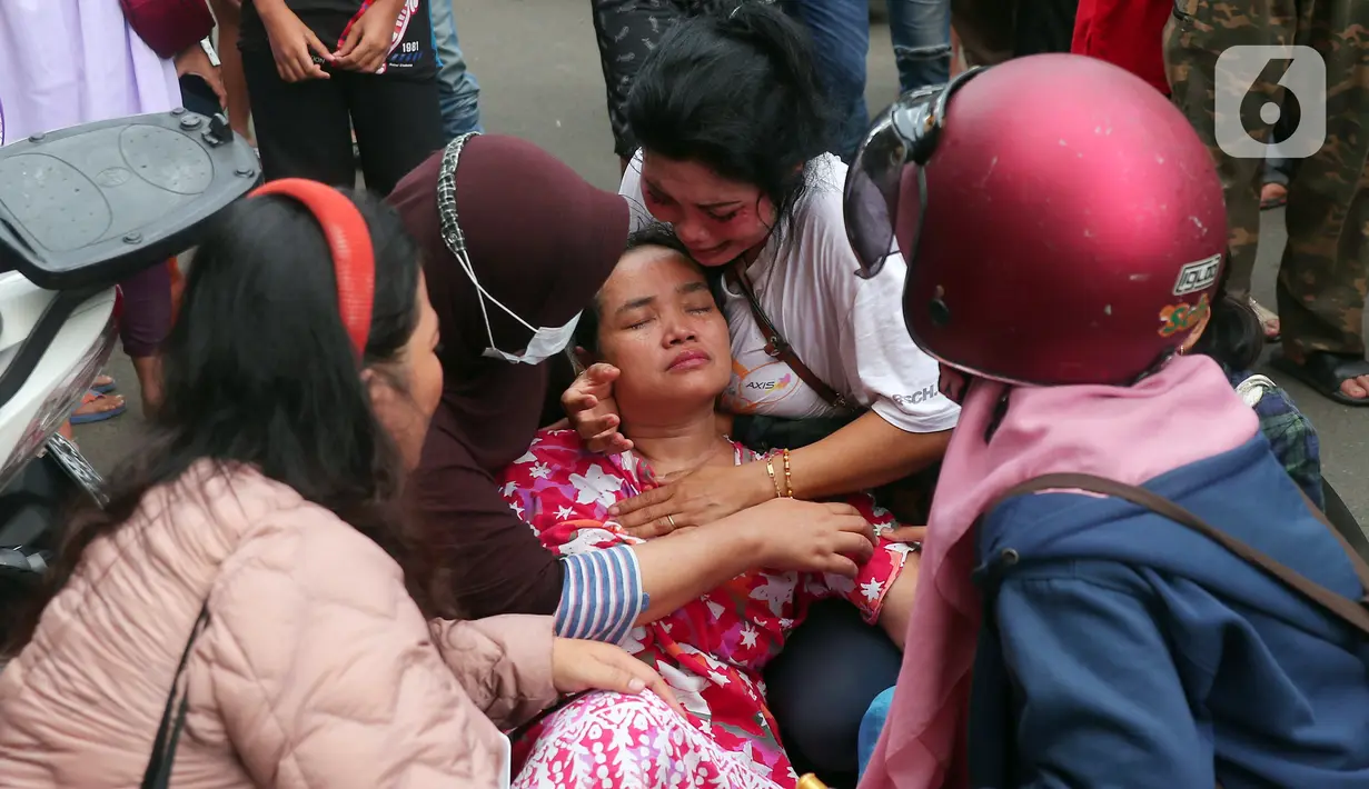 Warga mencoba menenangkan korban kebakaran di kawasan padat penduduk di Jalan Simprug Golf II RT 4/8, Grogol Selatan, Kebayoran Lama, Jakarta Selatan, Minggu (21/8/2022). Hingga siang ini, petugas pemadam kebakaran bersama warga masih terus berusaha untuk memadamkan api. (Liputan6.com/Angga Yuniar)