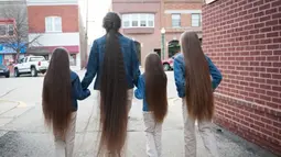 Terelynn Russel (43) dengan ketiga putrinya saat berjalan-jalan di Illinois, Amerika Serikat. Seumur hidupnya, Tere tidak pernah sekalipun menggunting rambutnya yang kini sudah hampir menyentuh tumit dengan panjang 1,87 meter. (dailymail.co.uk)